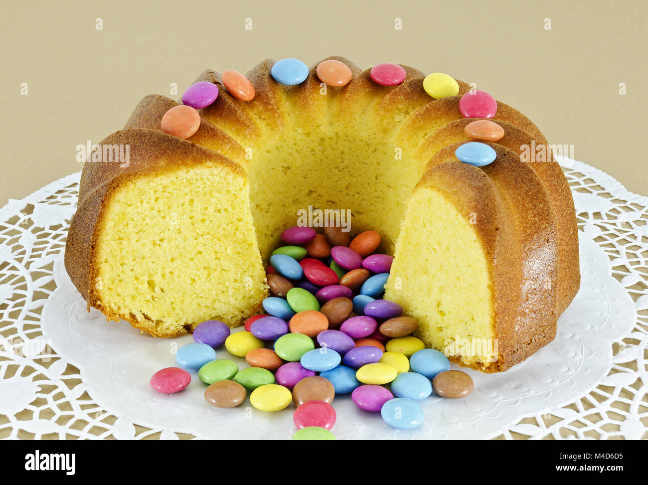 sliced ring-shaped sponge cake and sugar-coated chocolate confectionery Stock Photo