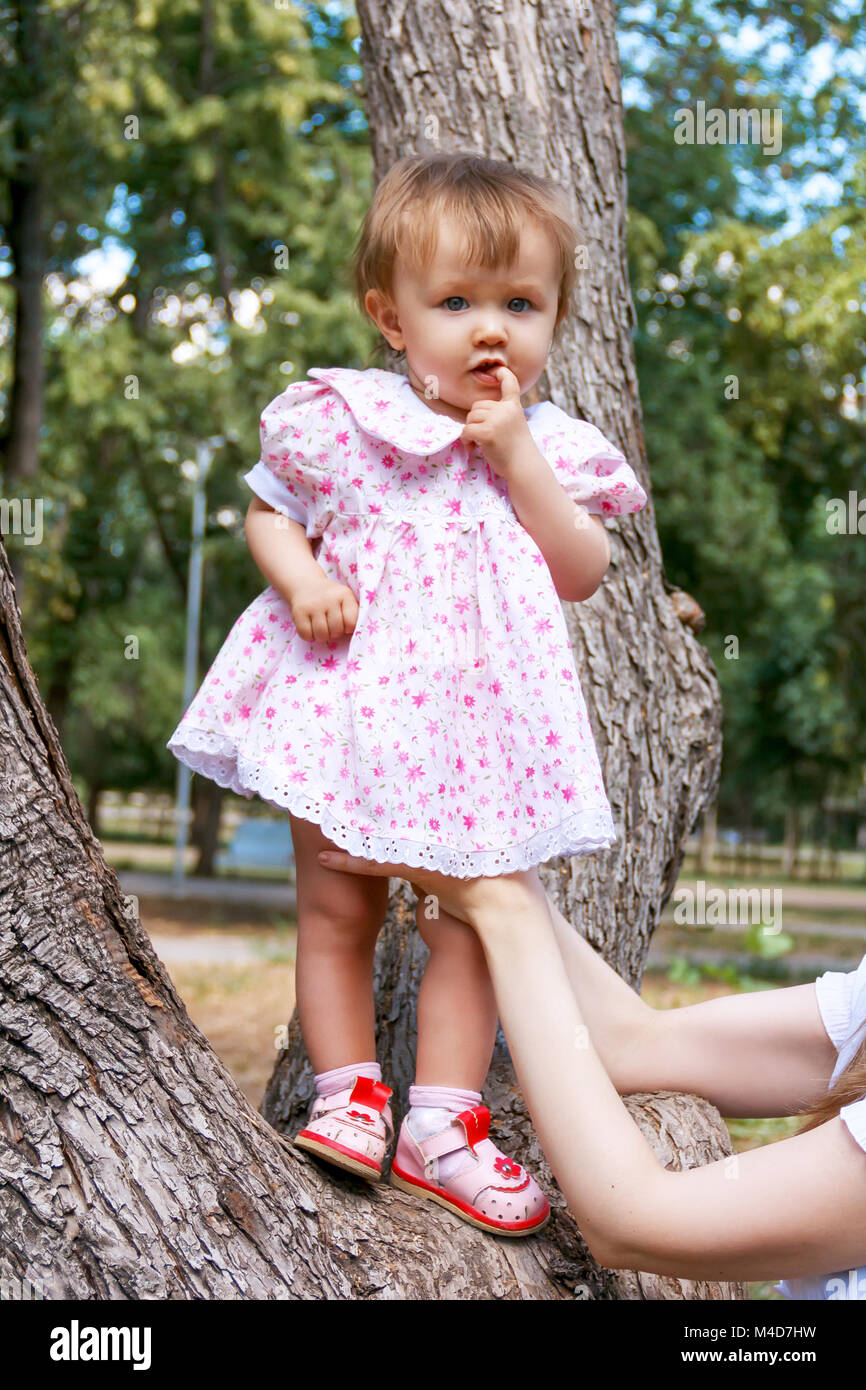 Cute infant in pink dress suckle finger Stock Photo