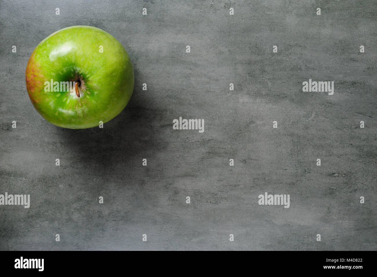 one green apple on dark stone background, top view. Stock Photo