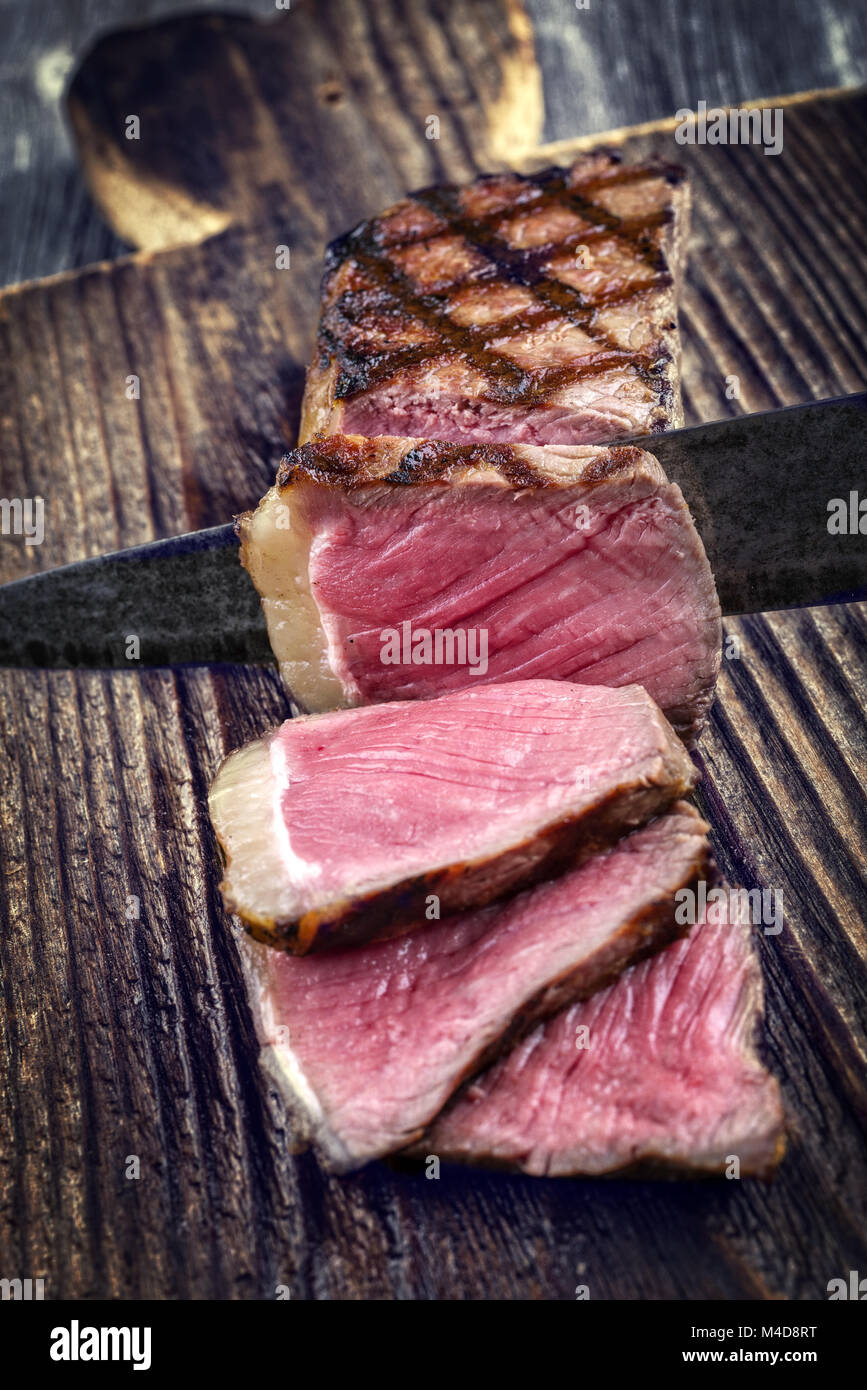 Barbecue New York Strip Steak on old Wooden Board Stock Photo