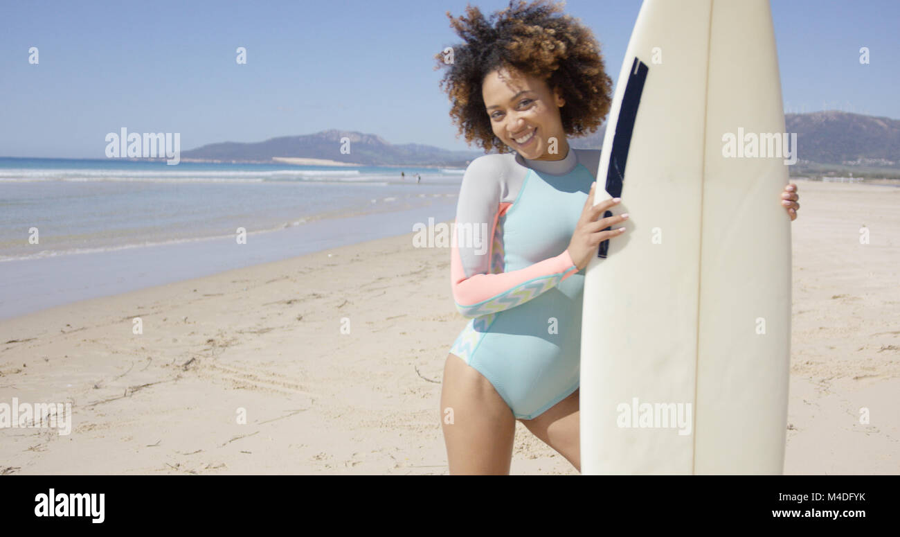 Smiling female standing with surfboard Stock Photo