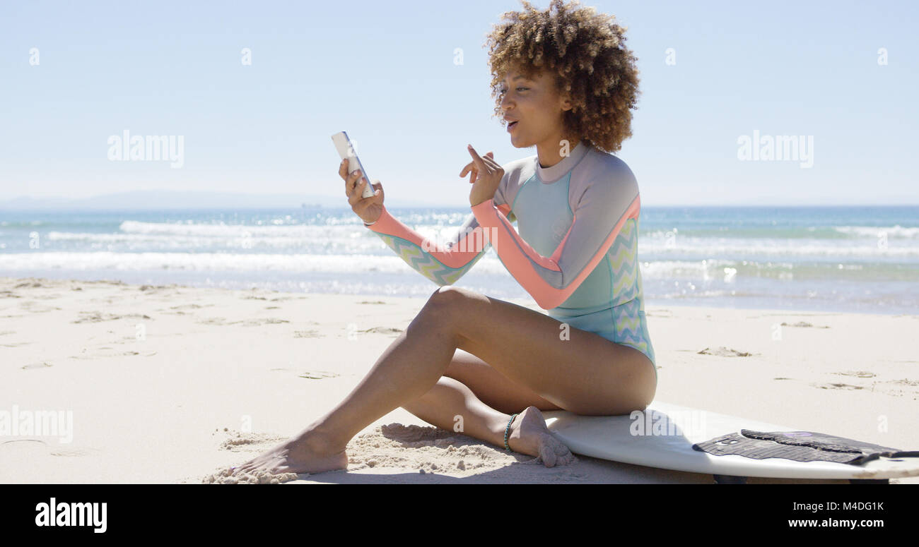 Smiling female on beach using smartphone Stock Photo