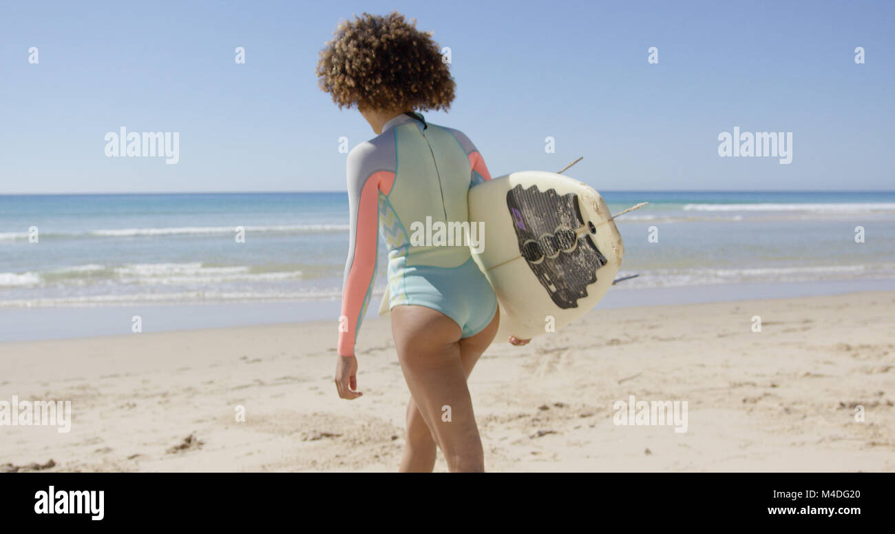 Female walking into sea to surf Stock Photo