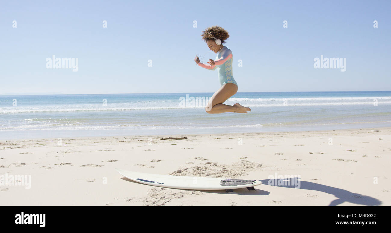 Female listening music and jumping on beach Stock Photo