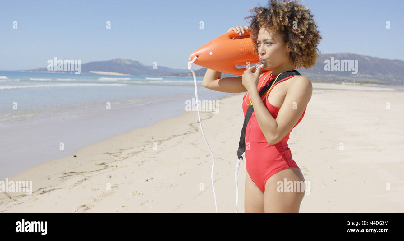 Lifeguard blowing a whistle holding rescue float Stock Photo