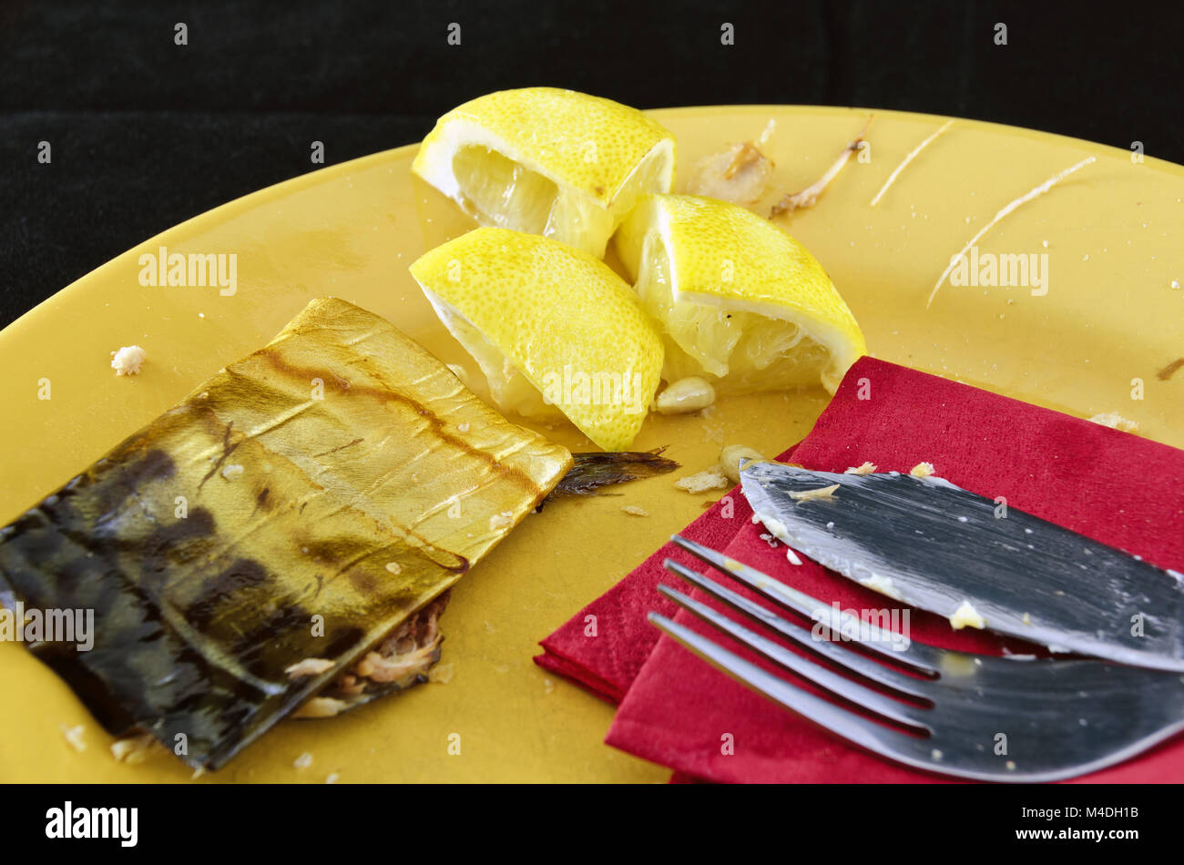 leftovers of smoked fish, lemons and dirty cutlery Stock Photo