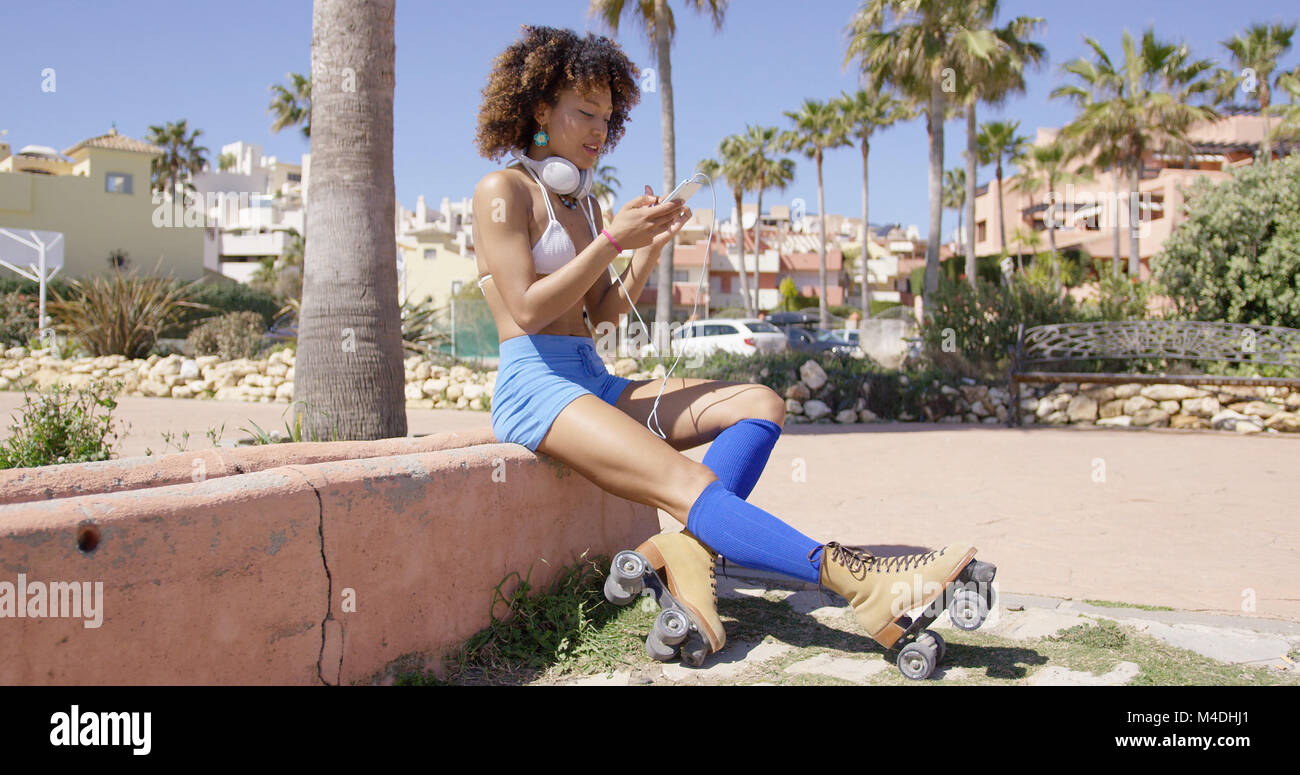 Female wearing rollerskates sitting on curb Stock Photo
