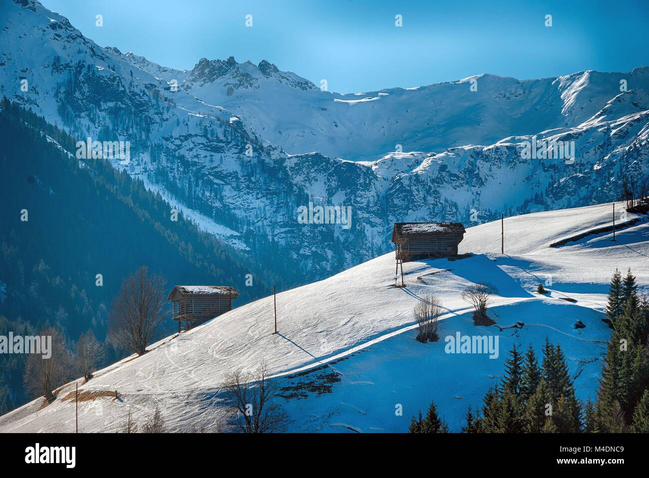 winter scenery in the mountains with wooden hay huts Stock Photo