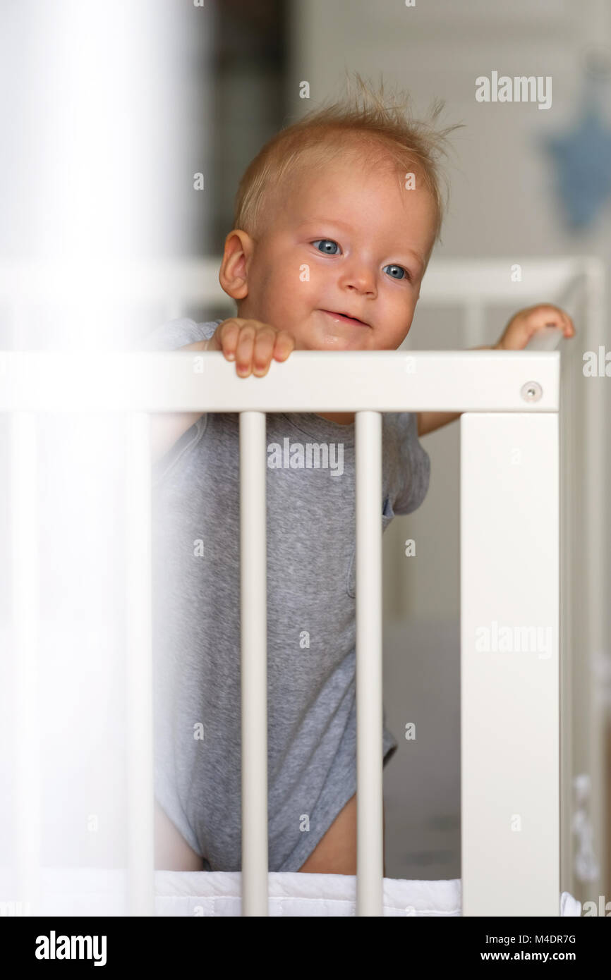 Baby boy standing in crib Stock Photo Alamy