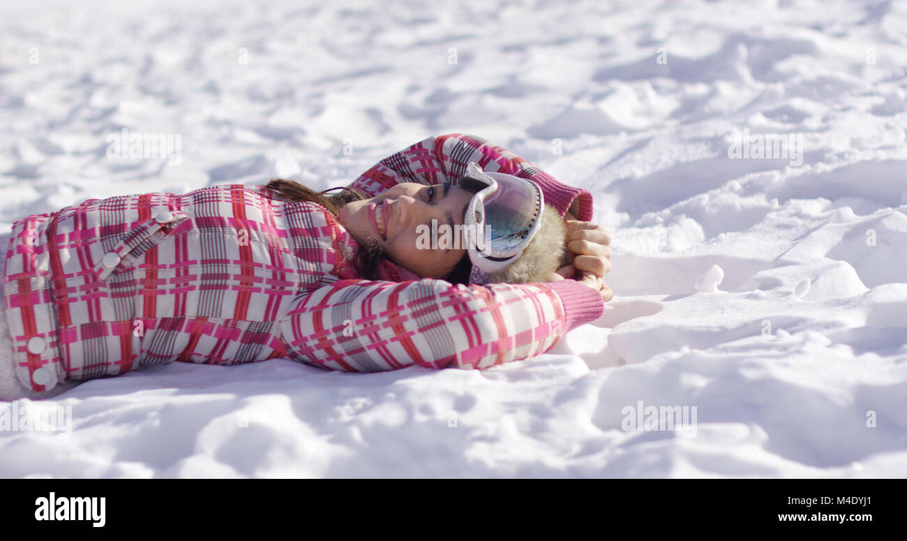 Young woman lying on snow with ski goggles Stock Photo