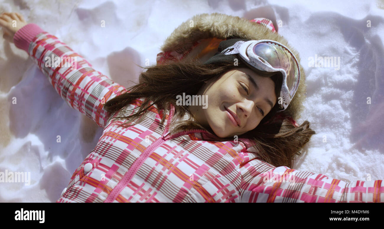 Young woman lying on snow with ski goggles Stock Photo