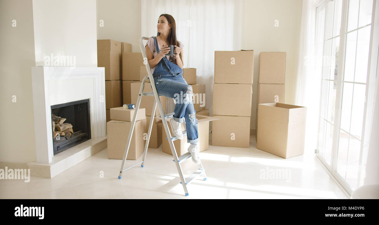 Young woman sitting on a stepladder Stock Photo