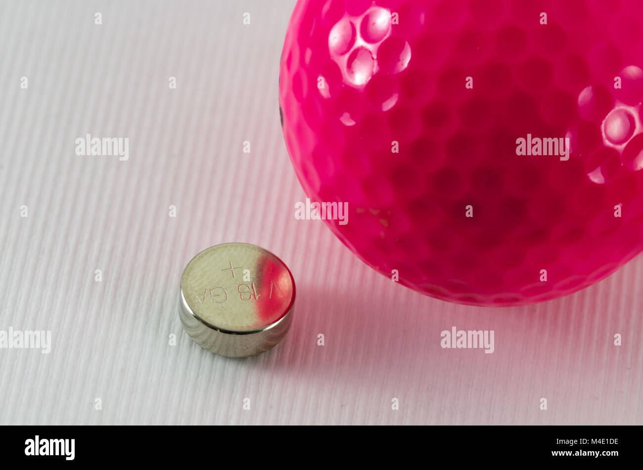 coin cell and pink coloured golf ball Stock Photo