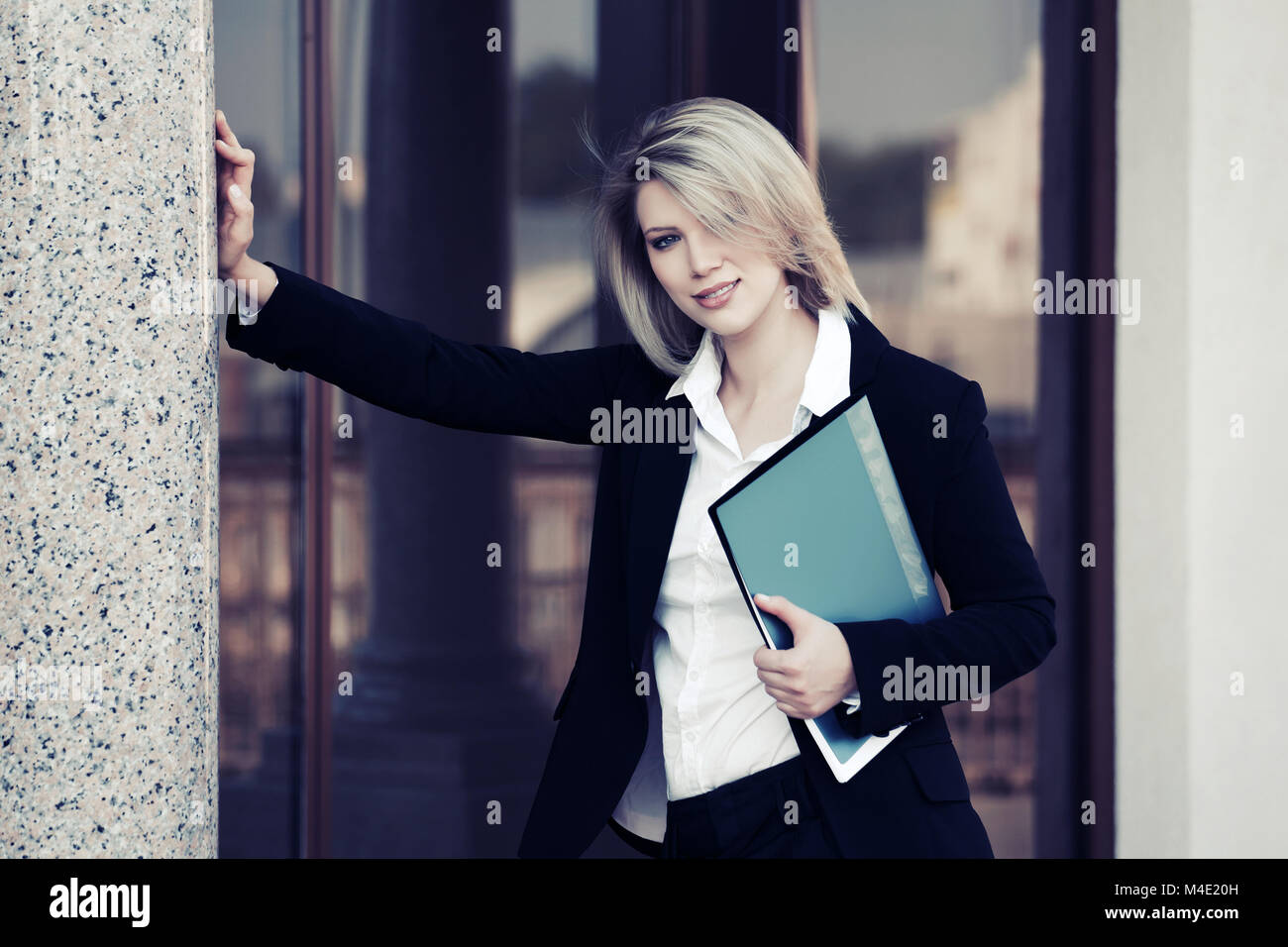 Happy young business woman with a folder at office building Stock Photo ...