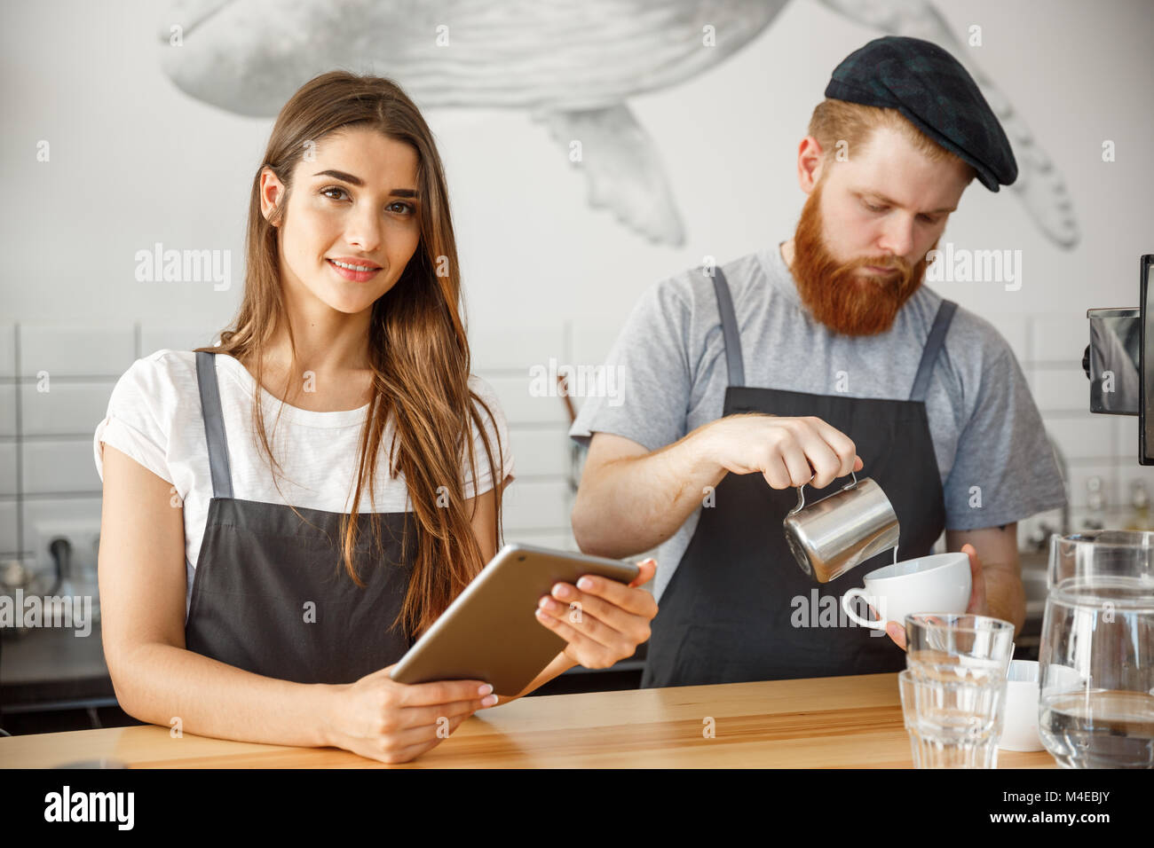Coffee Business Concept Cheerful baristas looking at their tablets