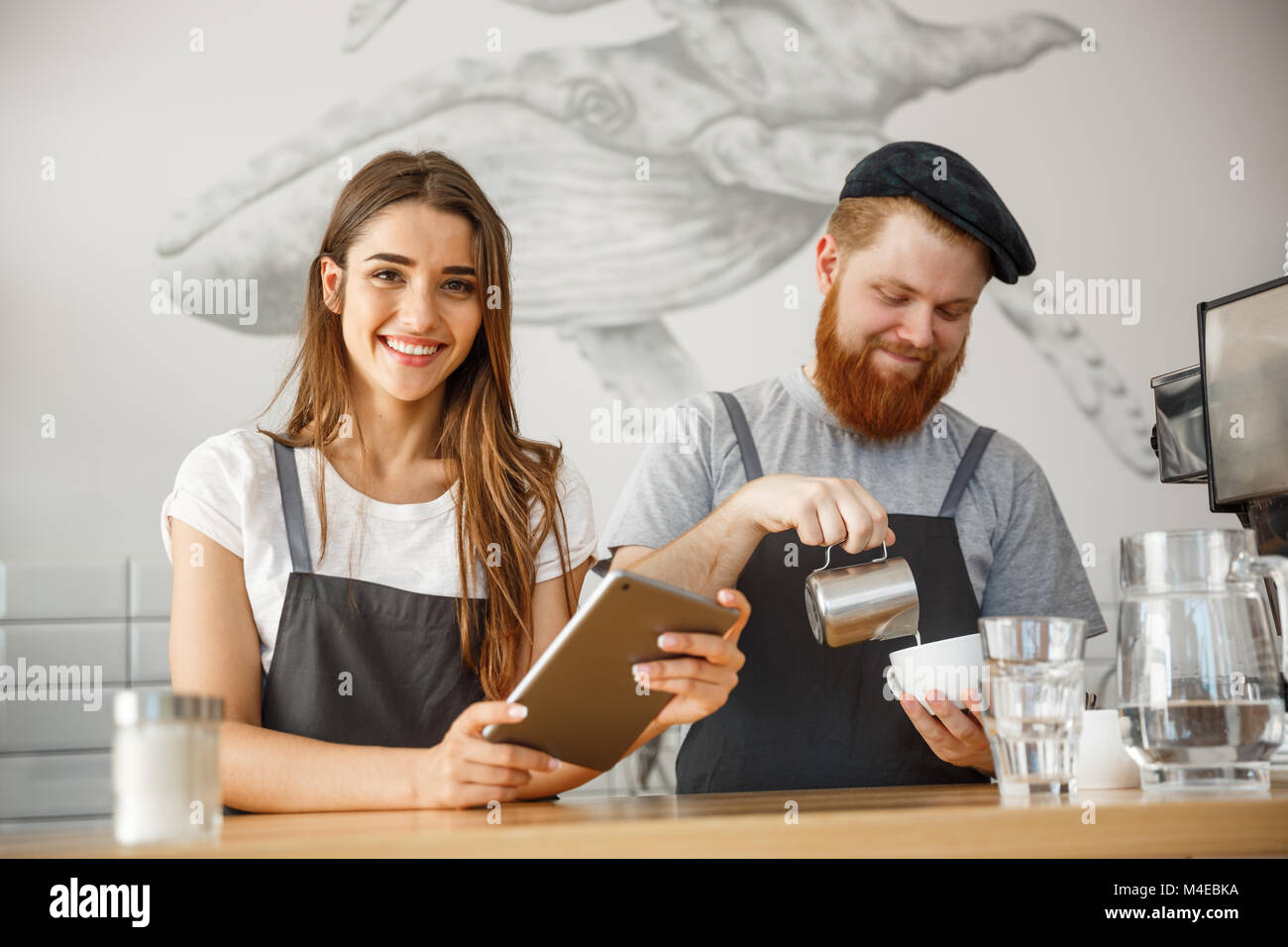 Coffee Business Concept Cheerful baristas looking at their tablets