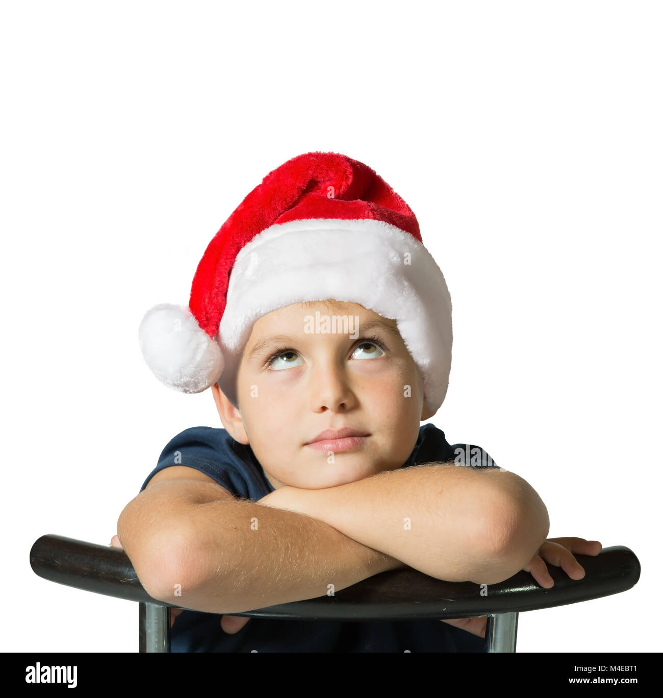 The boy in red Santa Claus's cap thoughtfully looks up Stock Photo