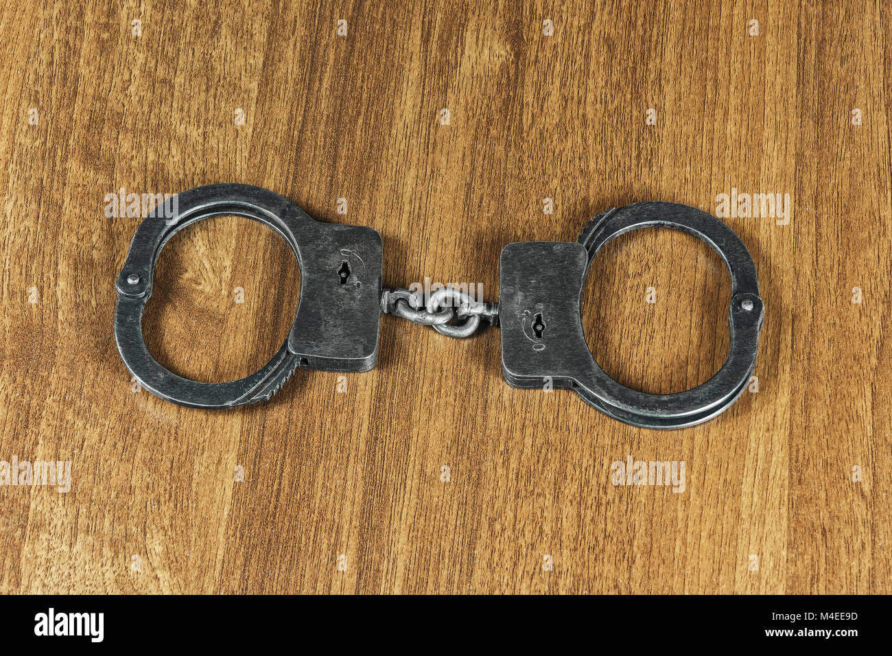 Police handcuffs lie on a wooden table Stock Photo