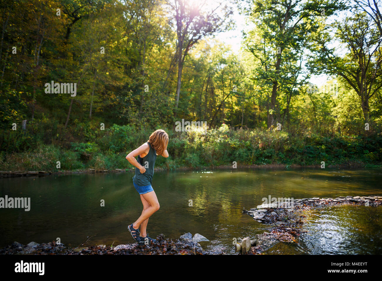 Woman walking along a riverbank Stock Photo - Alamy