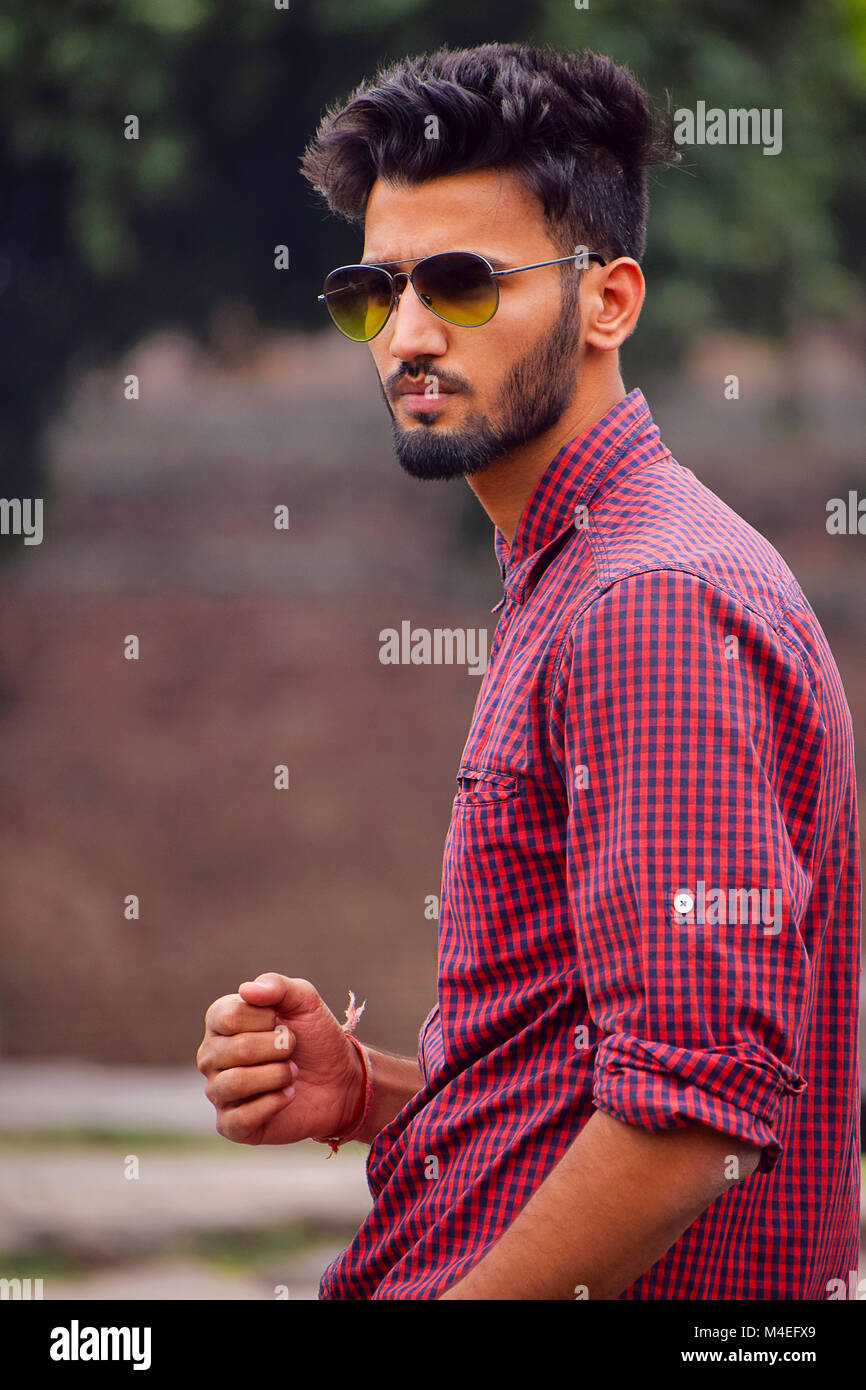 Young man with checked shirt posing in a garden, Pune, Maharashtra. Stock Photo