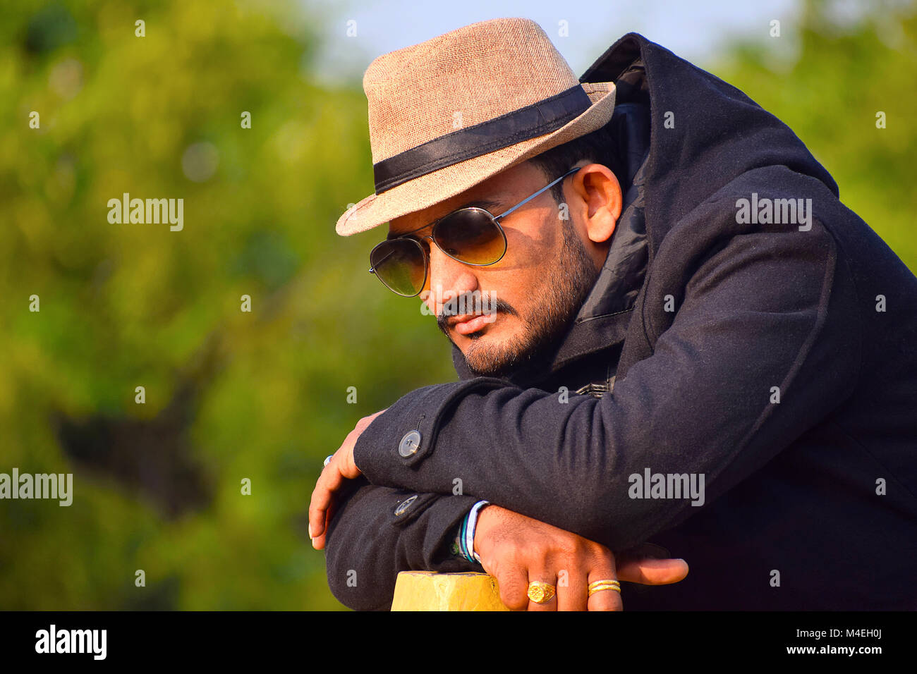 Man in a hat and black jacket in thinking pose, Pune, Maharashtra. Stock Photo