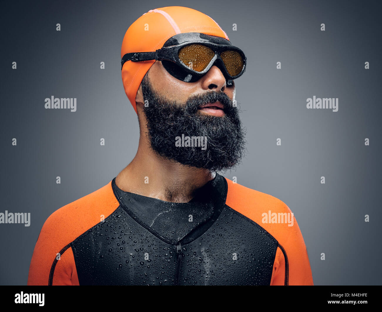 Bearded scuba diver male in orange neoprene suit isolated on grey