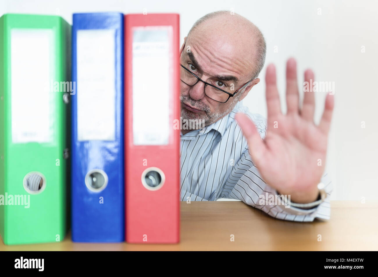 An official hides behind his files and signals rejection. Stock Photo