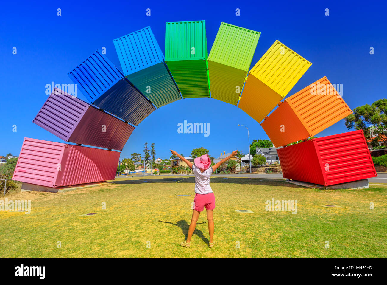 Fremantle, Australia - Jan 7, 2018: Happy woman with open arms looking Rainbow Sea Container in Fremantle, Western Australia. Female tourist enjoys at Fremantle welcome. Homosexuality and hope concept Stock Photo