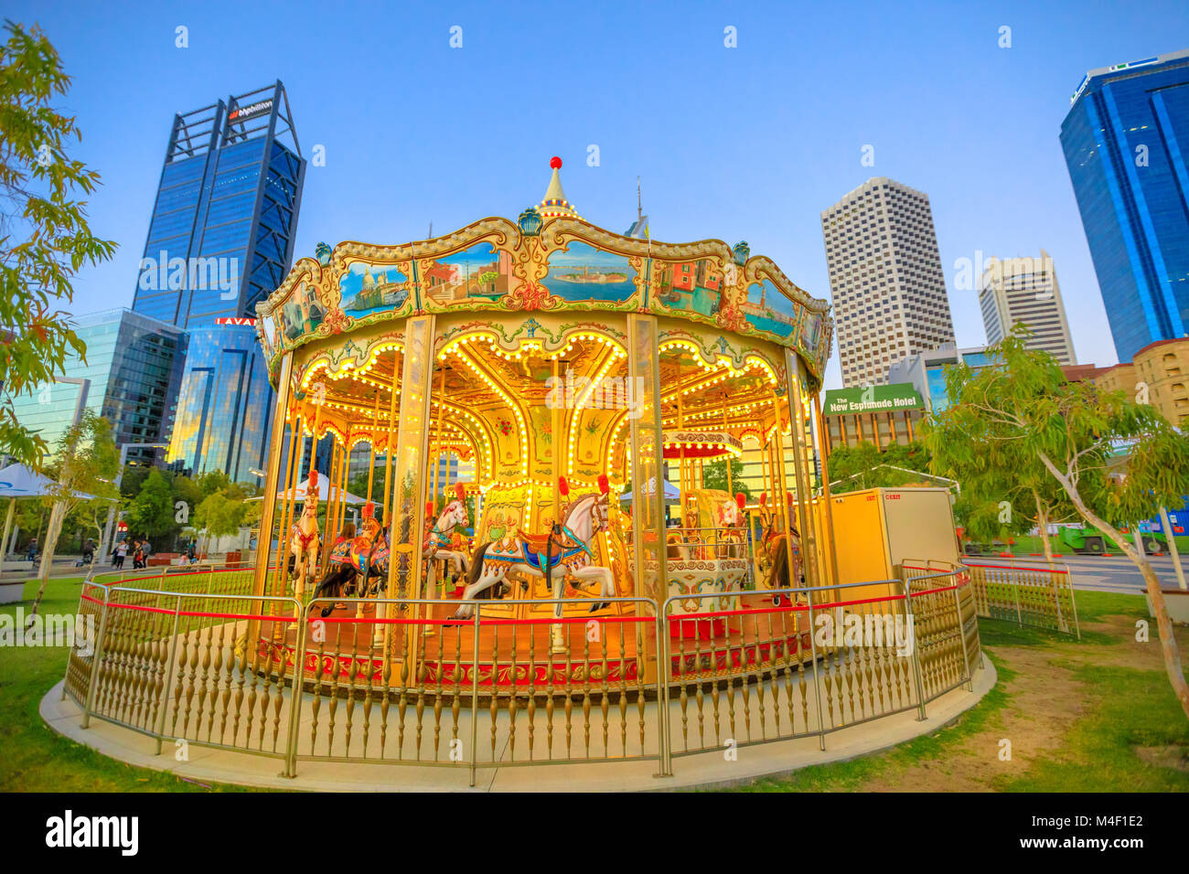 Perth, Australia - Jan 6, 2018: traditional Venetian Carousel at Elizabeth Quay, Perth, WA. Esplanade with modern skyscrapers of Central Business District on background. Blue hour shot. Urban scene. Stock Photo