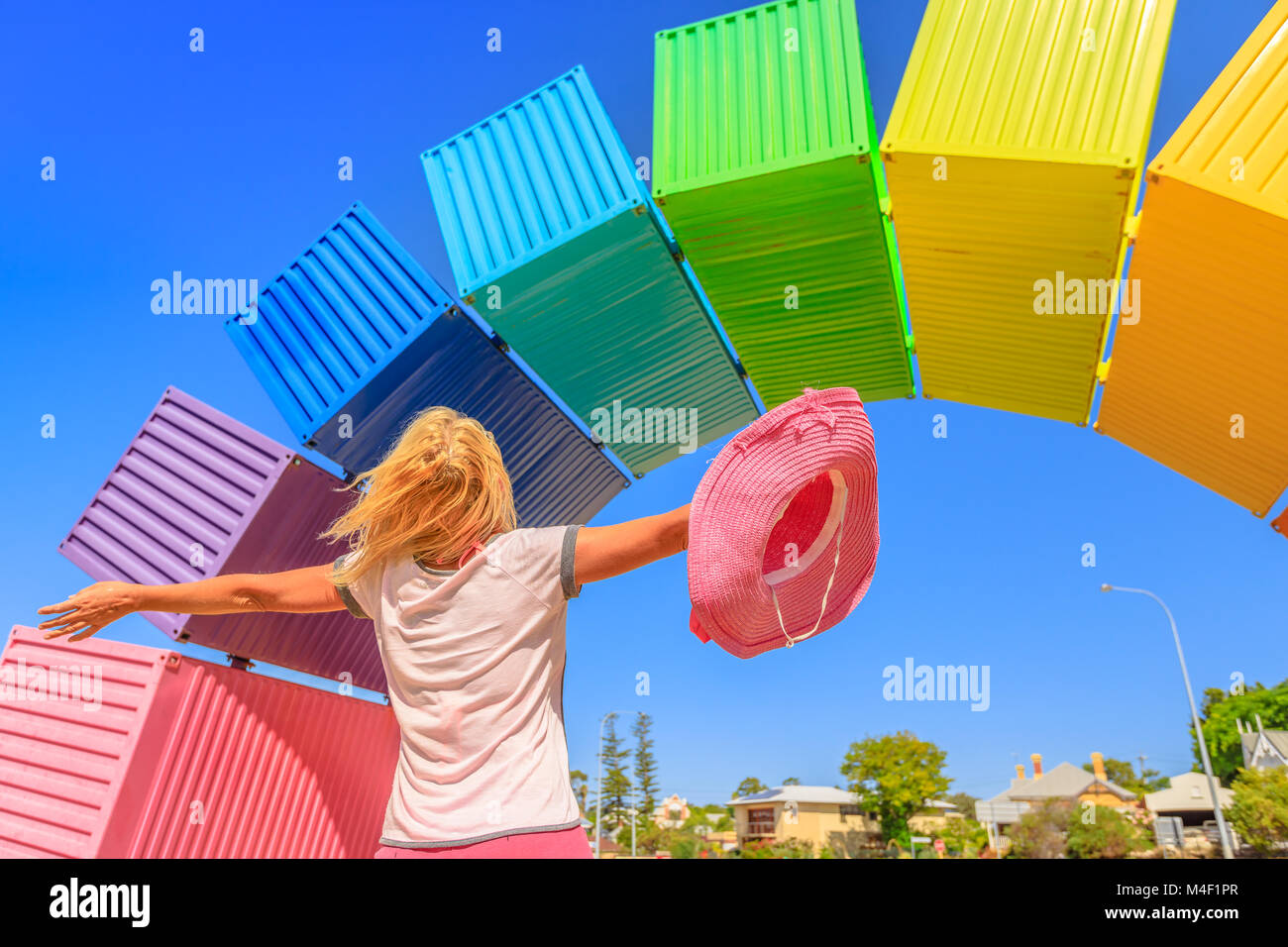 Fremantle, Australia - Jan 7, 2018: Carefree woman looking rainbow sea container in blurred background. Fremantle Port, Perth. Female tourist enjoys at Fremantle welcome.Homosexuality and hope symbol Stock Photo