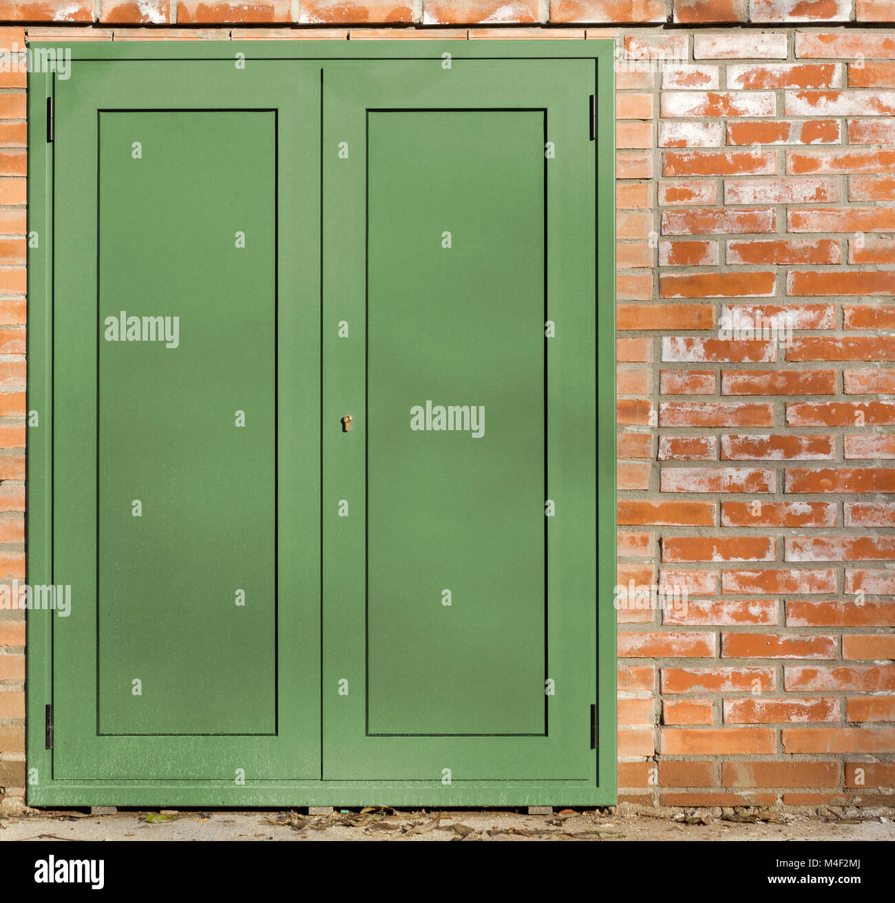 Green metal door on an exterior red brick wall Stock Photo