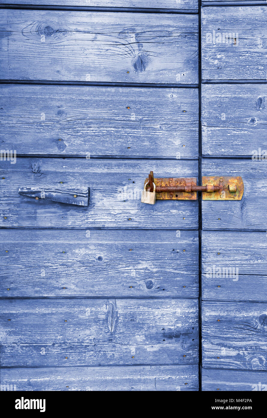 Old blue wooden door with peeling paint and rusty lock and handle Stock Photo