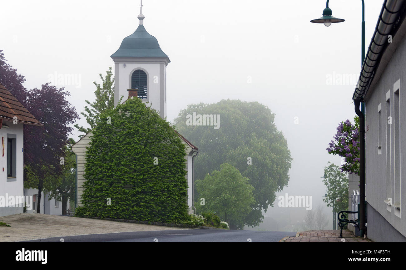village road with chapel on a foggy day Stock Photo