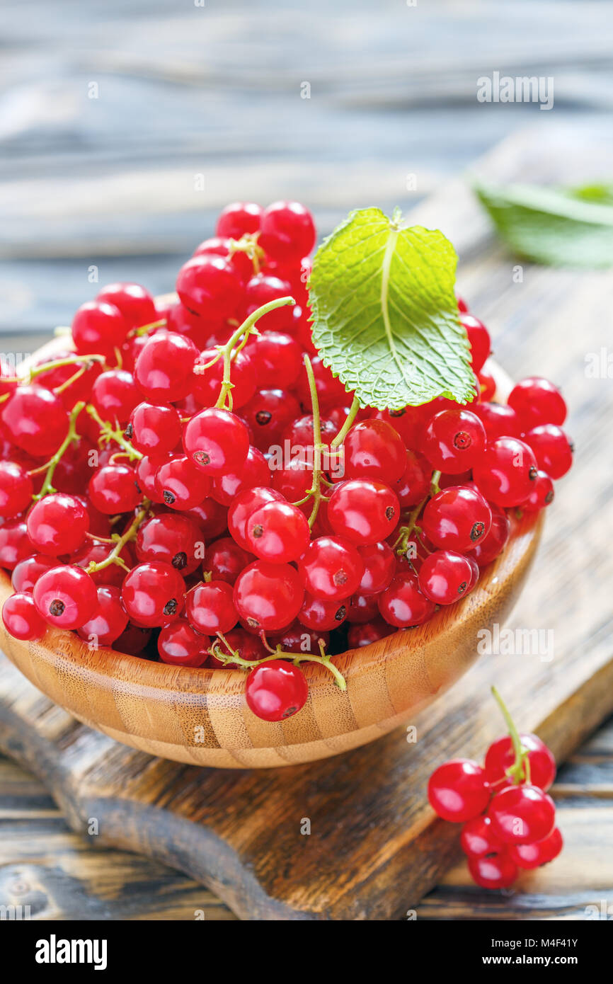 Bunches of red currant in a wooden bowl. Stock Photo