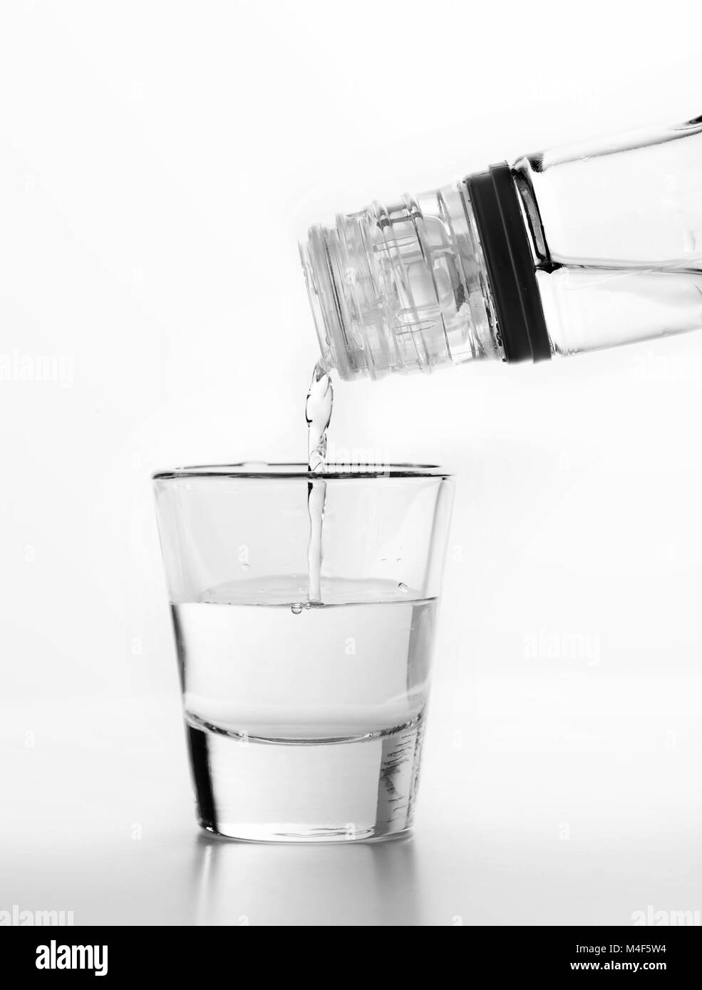 Vodka being poured to a glass. White background. Stock Photo