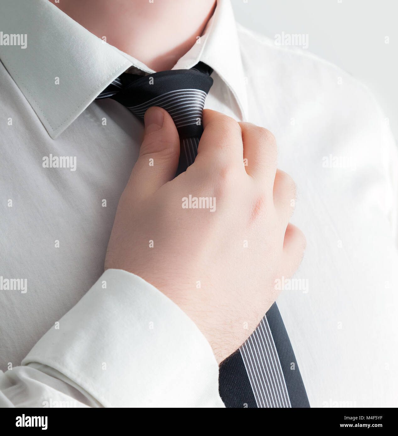 Businessman adjusting his tie, close-up. Stock Photo