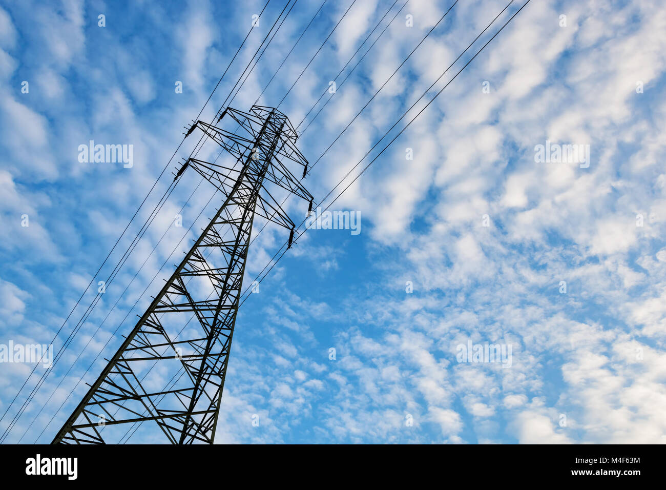 Electricity transmission pylon against blue sky with fluffy clouds Stock Photo