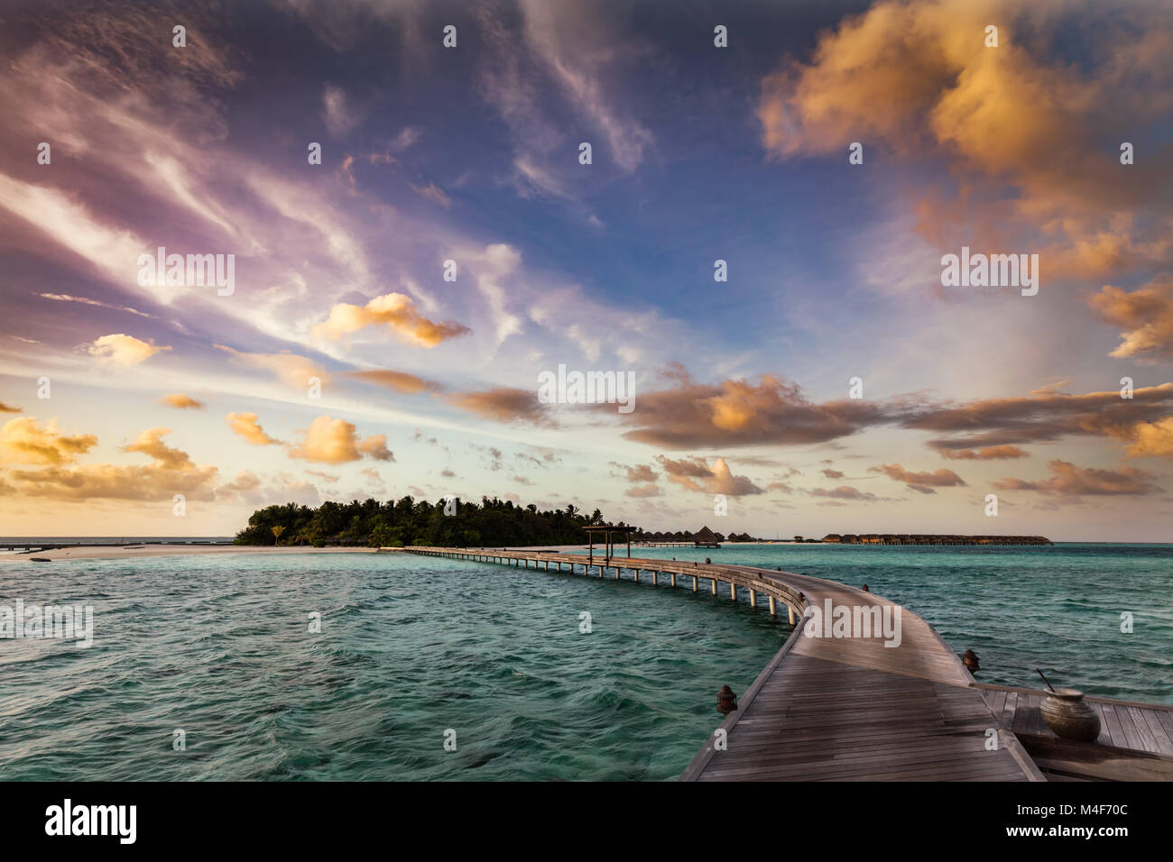 Wooden jetty towards a small island in Maldives at sunset Stock Photo