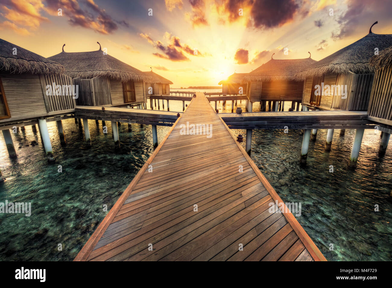 Wooden jetty and water villas. Maldives island resort at sunset Stock Photo