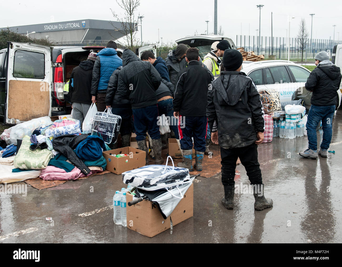 Grande-Synthe, Northern France. 31 January 2016. A delivery of aid by Belgian aid agency, Hasane is delivered and distributed to the Grande-Synthe refugee camp close to the port of Dunkirk in Northern France. In the camp conditions are grim in part due to thick mud and a lack of basic amenities. Families live in rain soaked tents and huddle around small fires for basic heat. Stock Photo