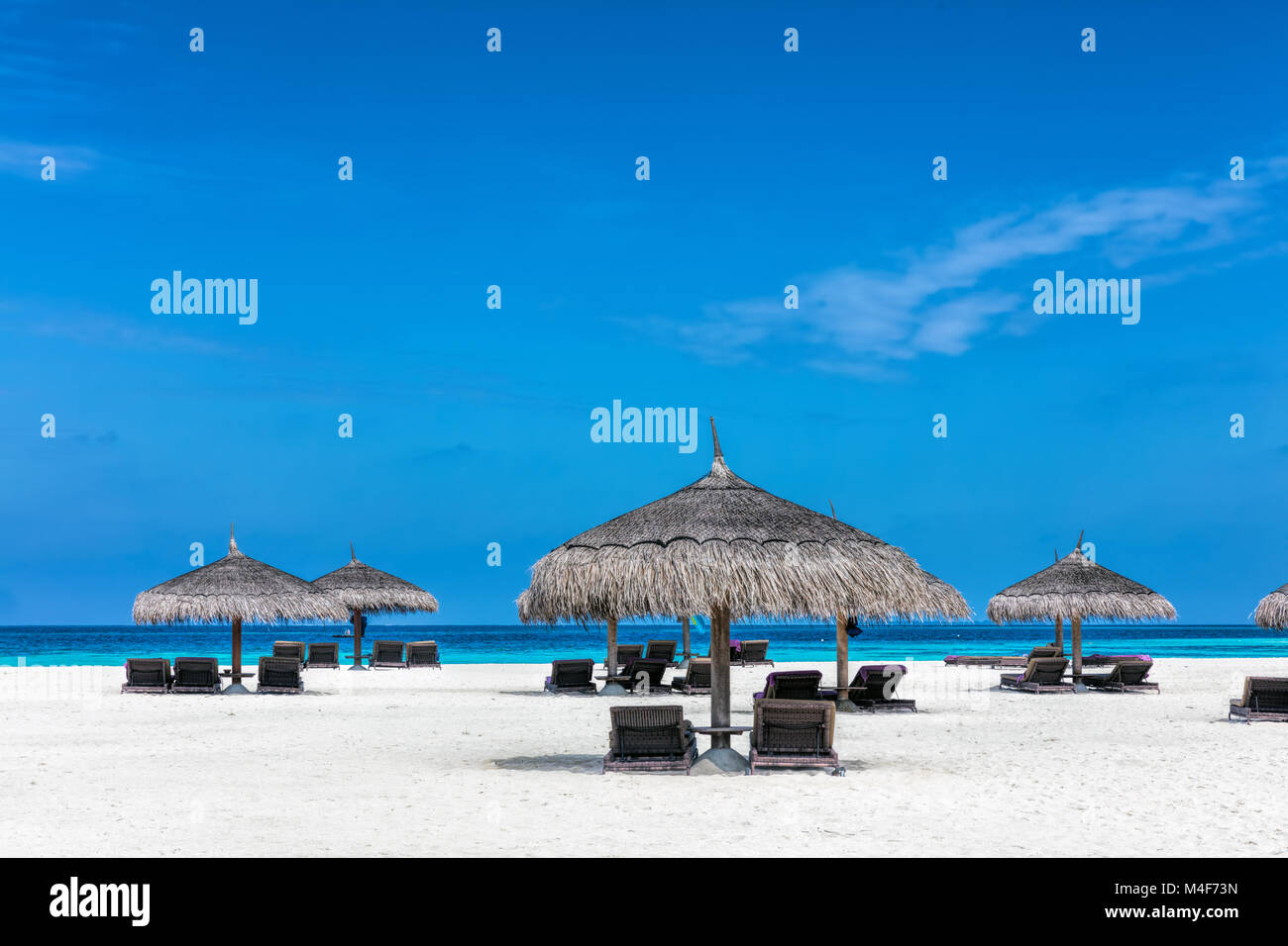 Sandy tropical beach with deckchairs and sunshades. Maldives Stock Photo