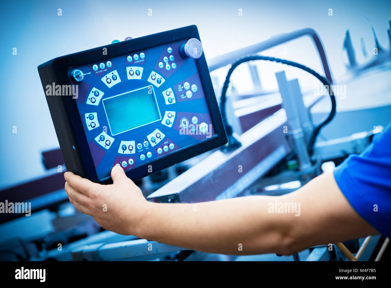 Worker programming print screening machine on the monitor. Stock Photo
