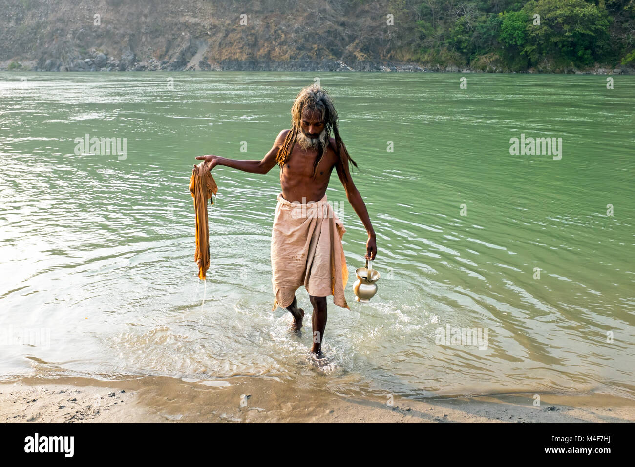 RAM JHULA, INDIA - APRIL 17, 2017: Indian sadhu comes out of the river Ganges after a bath and washing his clothes on 17th of april 2017 in India Stock Photo