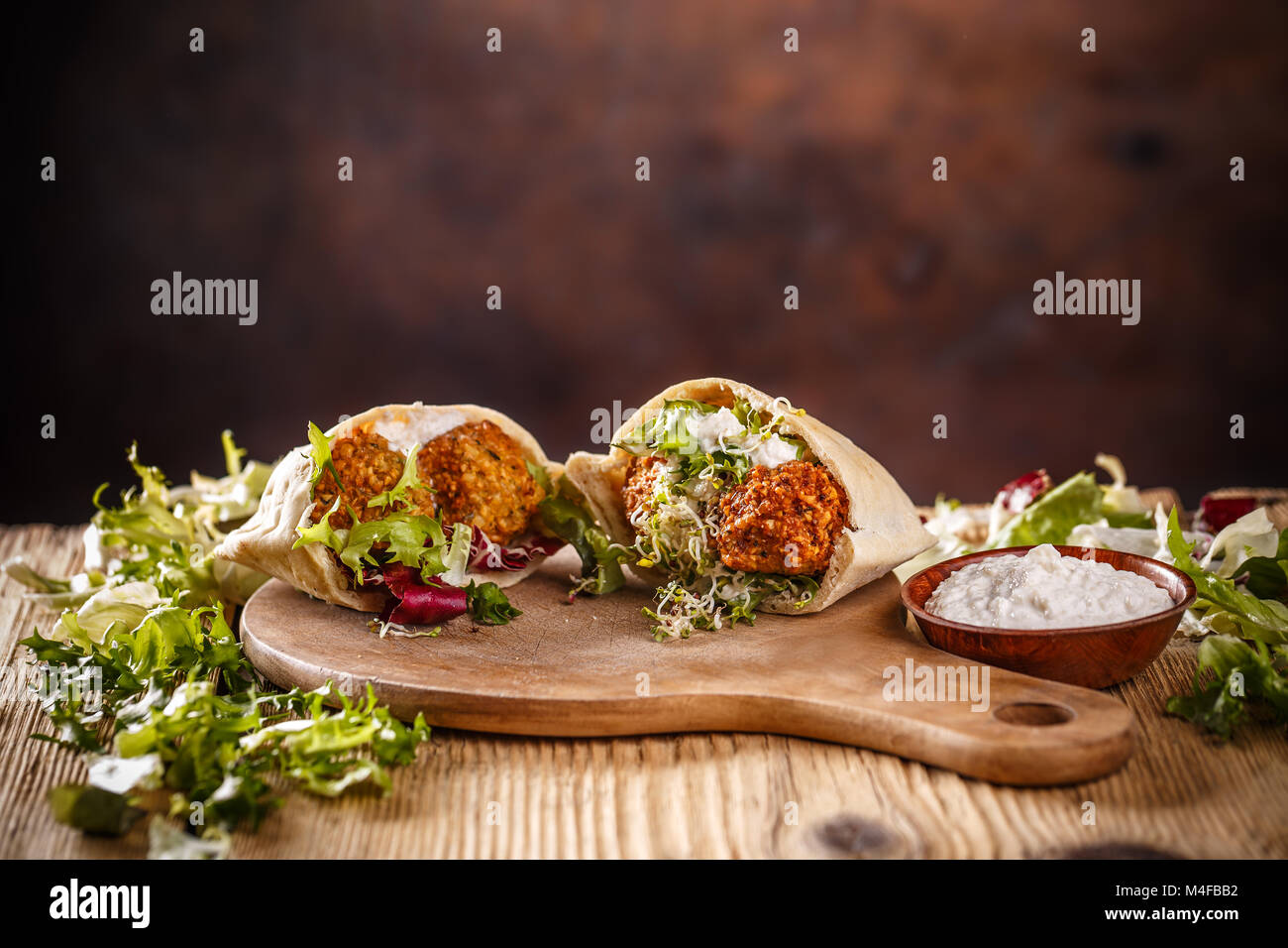 Pita bread filled with falafel, salad and white sauce Stock Photo
