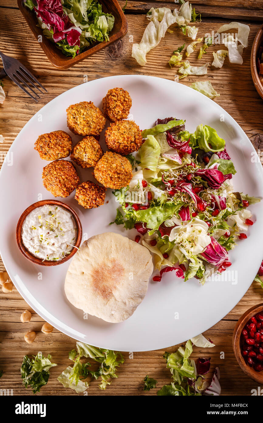 Chickpea falafel balls on a wooden desk with vegetables Stock Photo