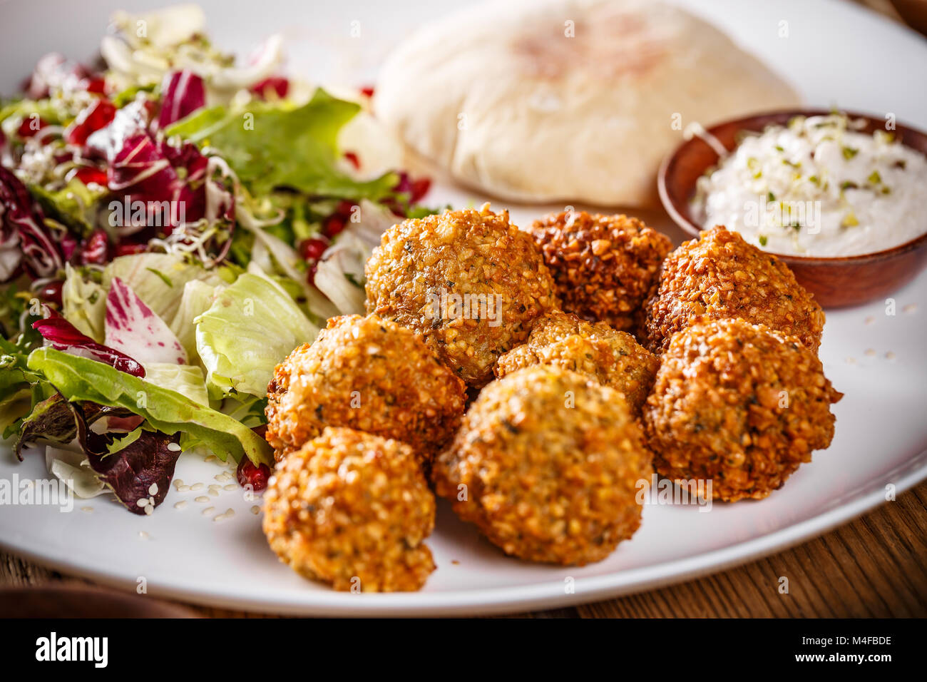 Chickpea falafel balls on a wooden desk with vegetables Stock Photo