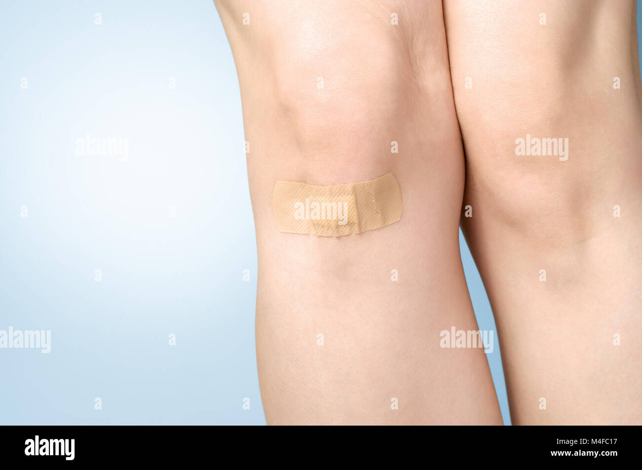 Female leg with adhesive bandage on blue background Stock Photo