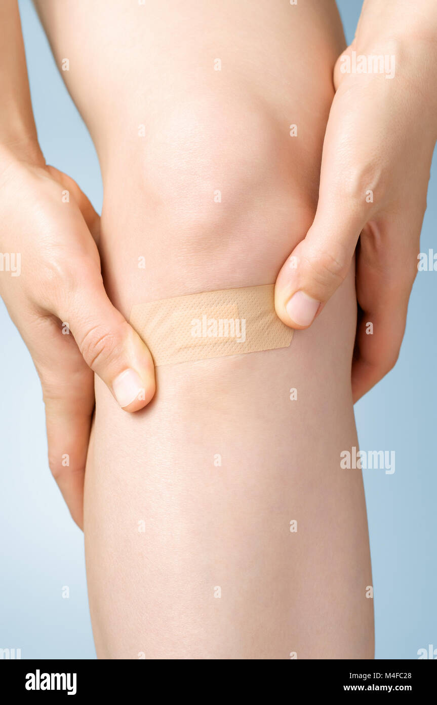 Woman putting an adhesive bandage on her leg Stock Photo