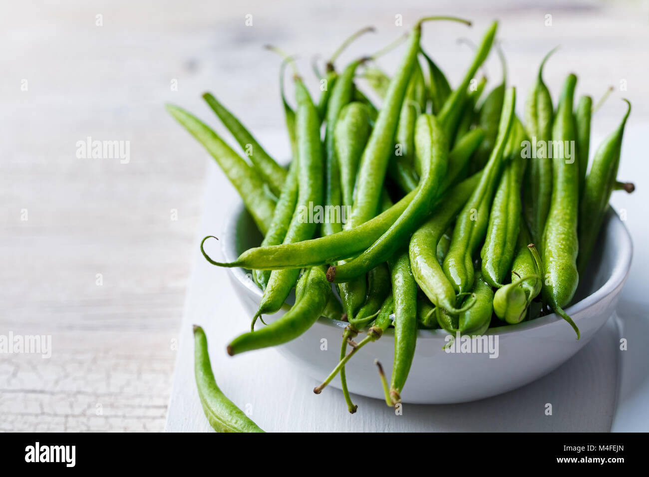 Green beans in white bowl on cutting board. Stock Photo