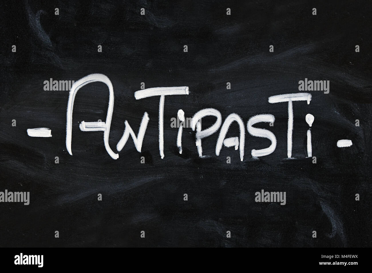 Close up white chalk ANTIPASTI word over hand written over background
